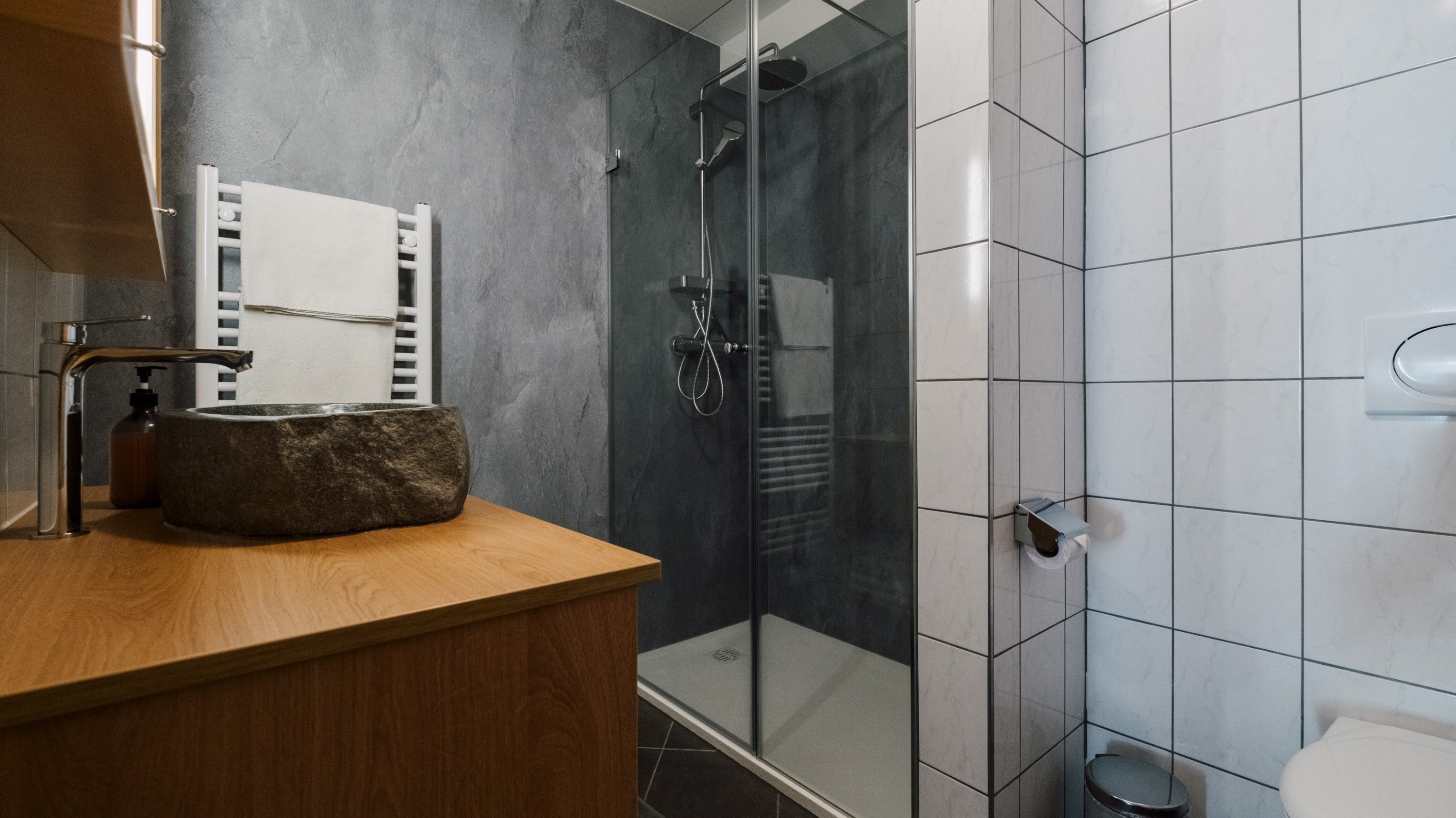 Modernes Badezimmer mit eleganter Gestaltung Moderner Badbereich mit Glasdusche, Steinschüssel und Holzwaschtisch, geflieste Wände