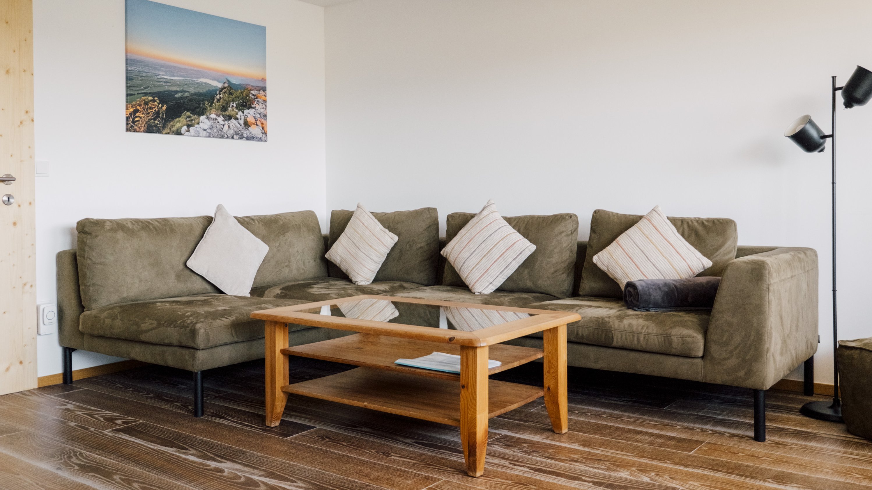 Eine einladende Wohnzimmereinrichtung mit einem U-förmigen Sofa, Kissen, einem Holztisch und einer Stehlampe.