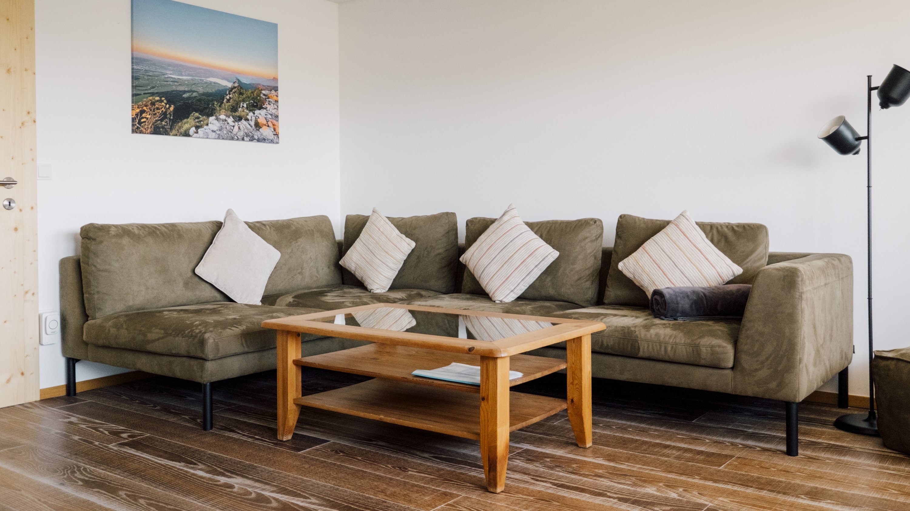 Eine einladende Wohnzimmereinrichtung mit einem U-förmigen Sofa, Kissen, einem Holztisch und einer Stehlampe.
