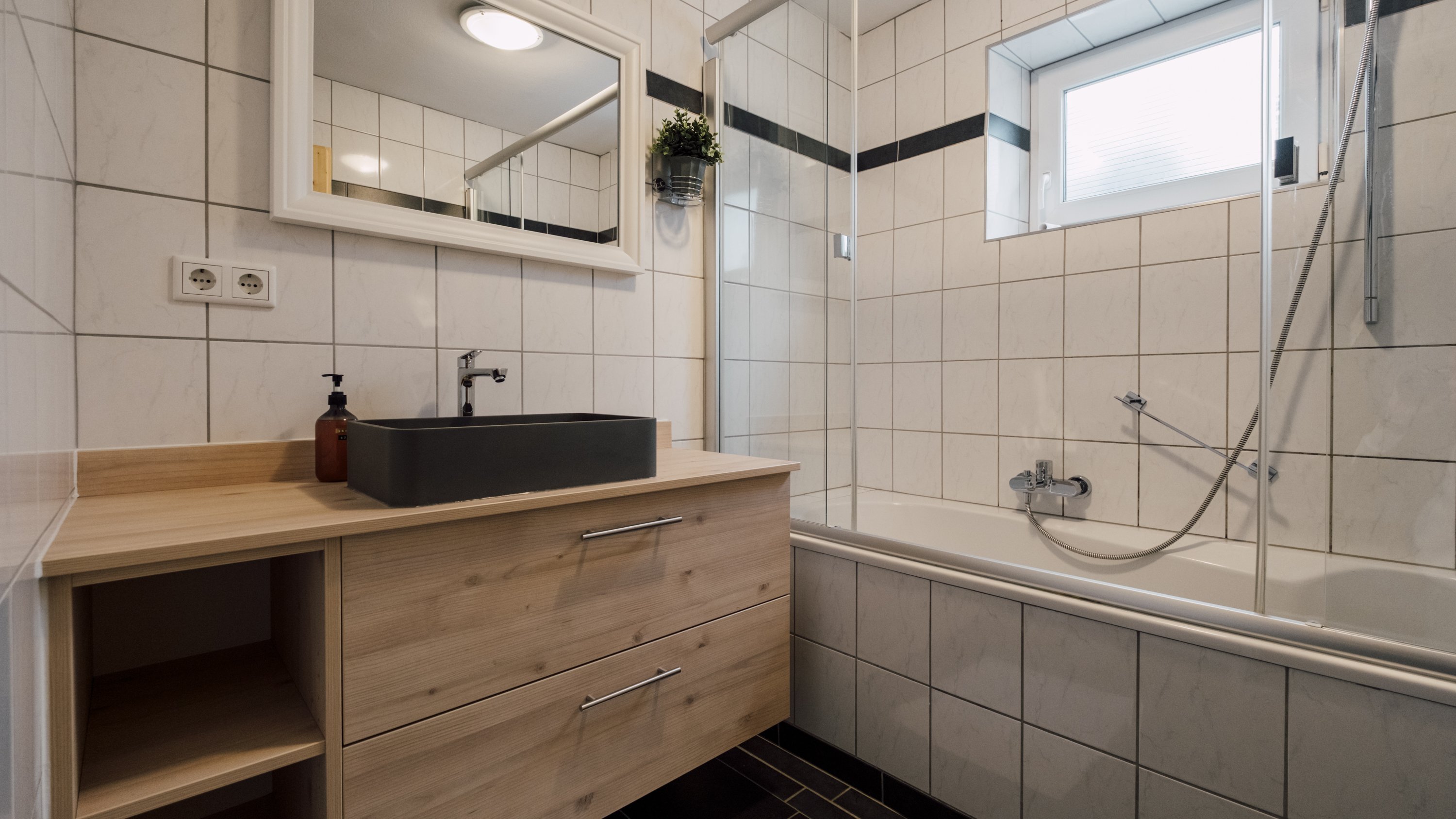 Helles Badezimmer mit Badewanne, Dusche und Waschbecken in stilvollem Design und großem Spiegel