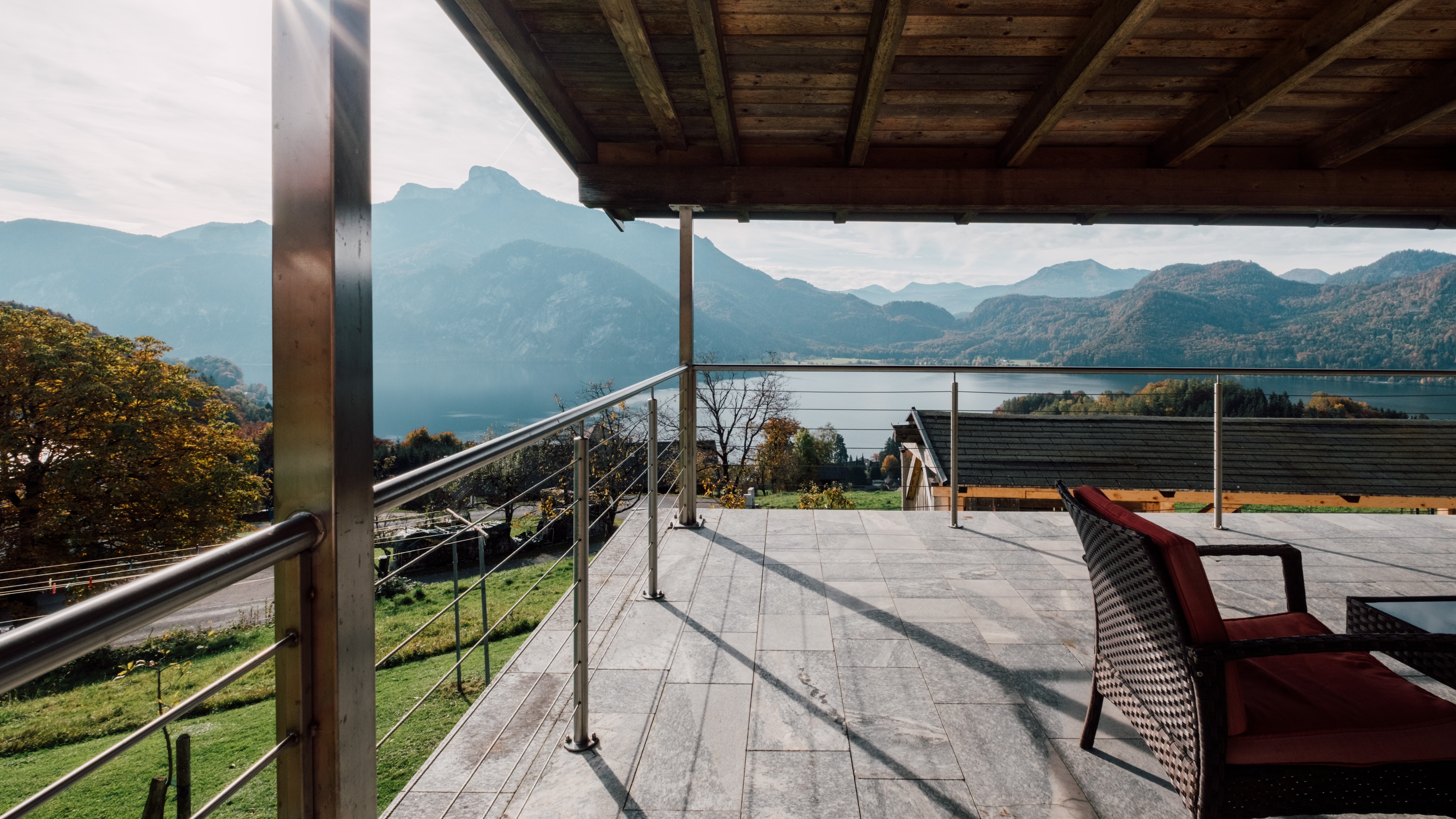 Moderne Terrasse mit Blick auf Berge und See, Holzstruktur und bequemer Stuhl sichtbar