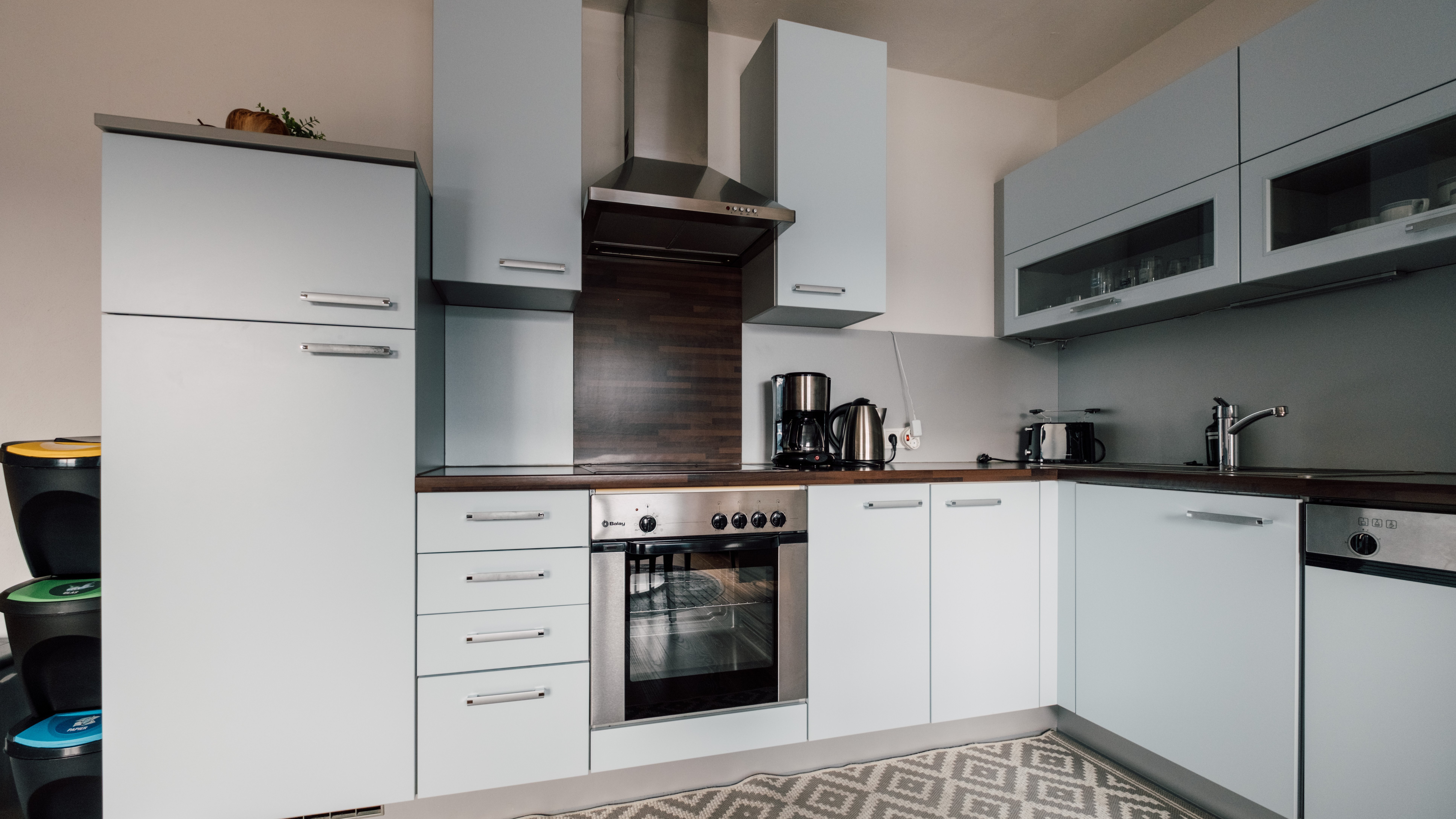 Moderne Küche für anspruchsvolles Kochen Eine moderne Küche mit hellblauen Schränken und Holzarbeitsplatte sowie Edelstahlgeräten