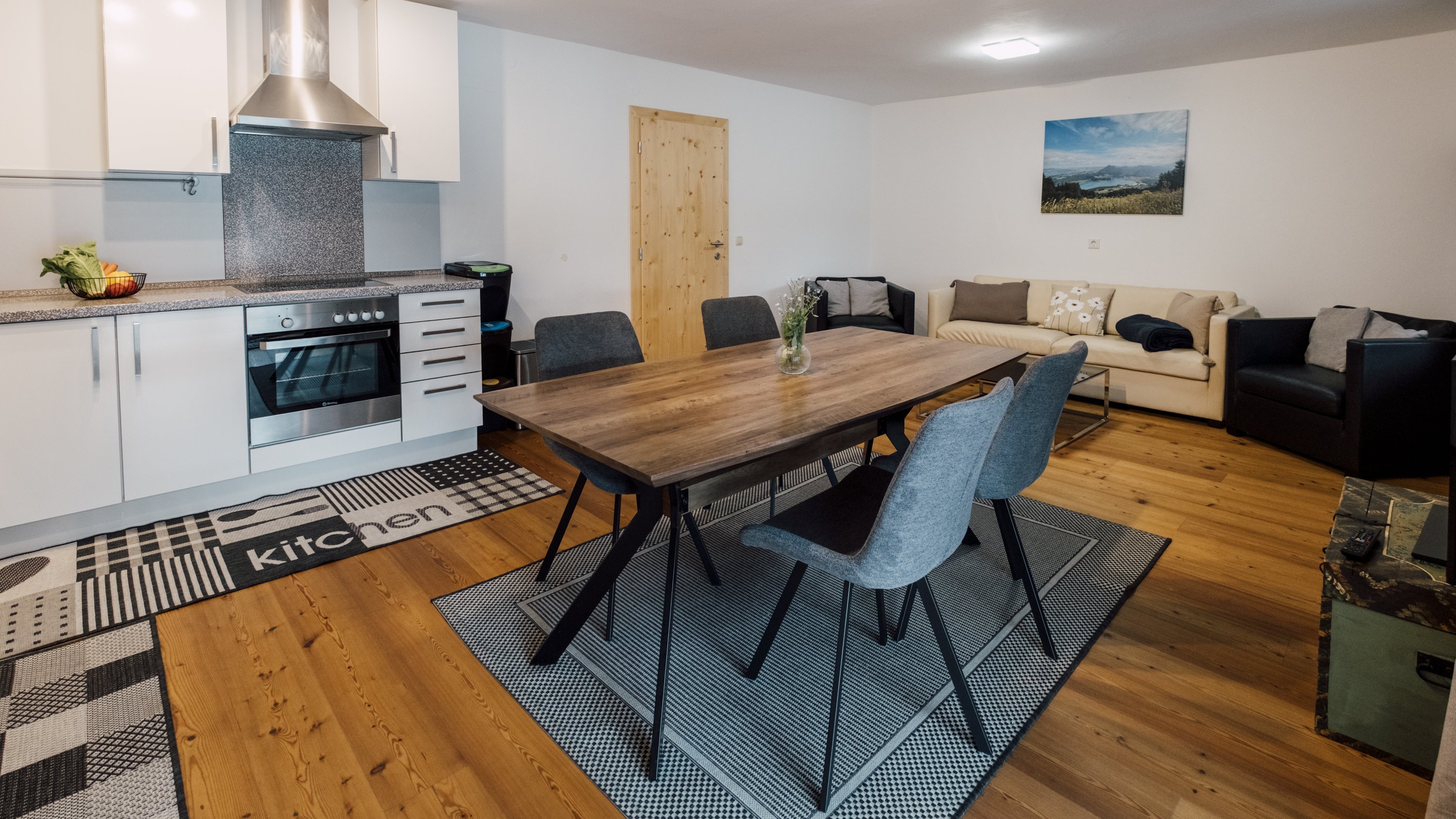 Ein offener Wohnraum mit einer modernen Küche und einem Holz-Esszimmertisch samt Stühlen