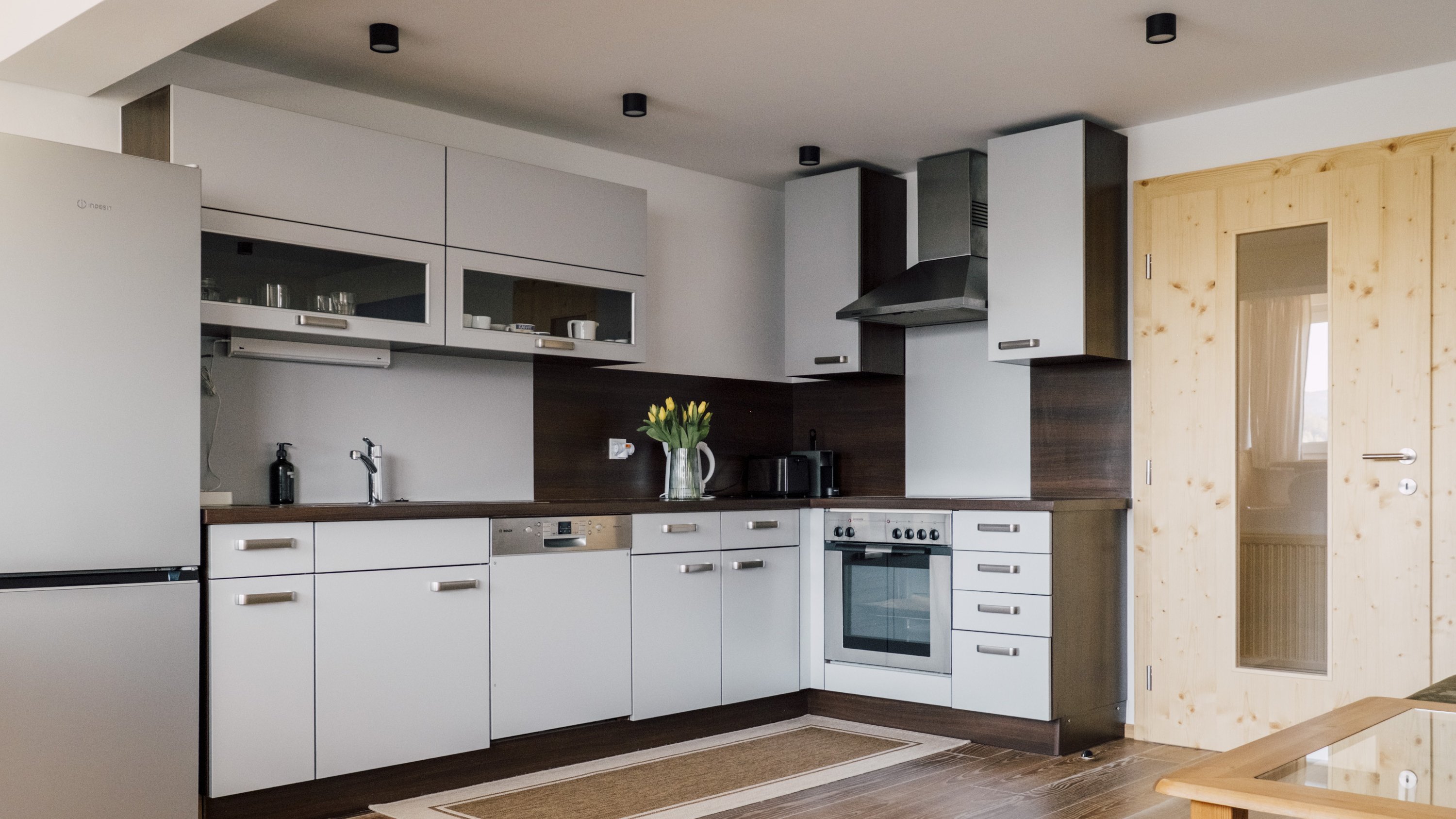 Moderne Küche mit schlichten Schränken und einem Kühlschrank aus Edelstahl sowie einem Herd mit Backofen