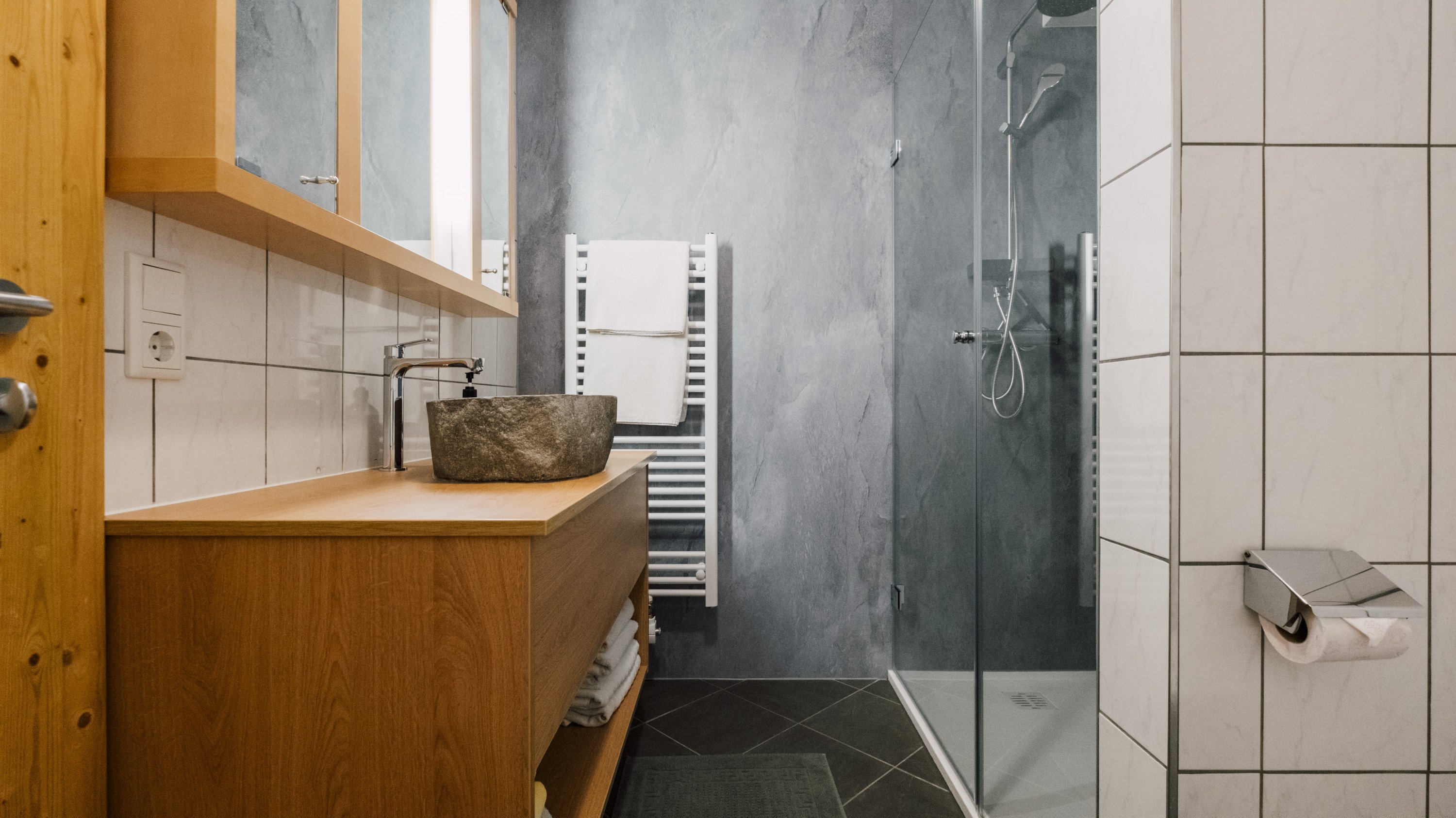 Modernes Badezimmer mit minimalistischer Ästhetik Helles Badezimmer mit gläserner Dusche und Holzwaschtisch, stilvoll gefliestem Boden