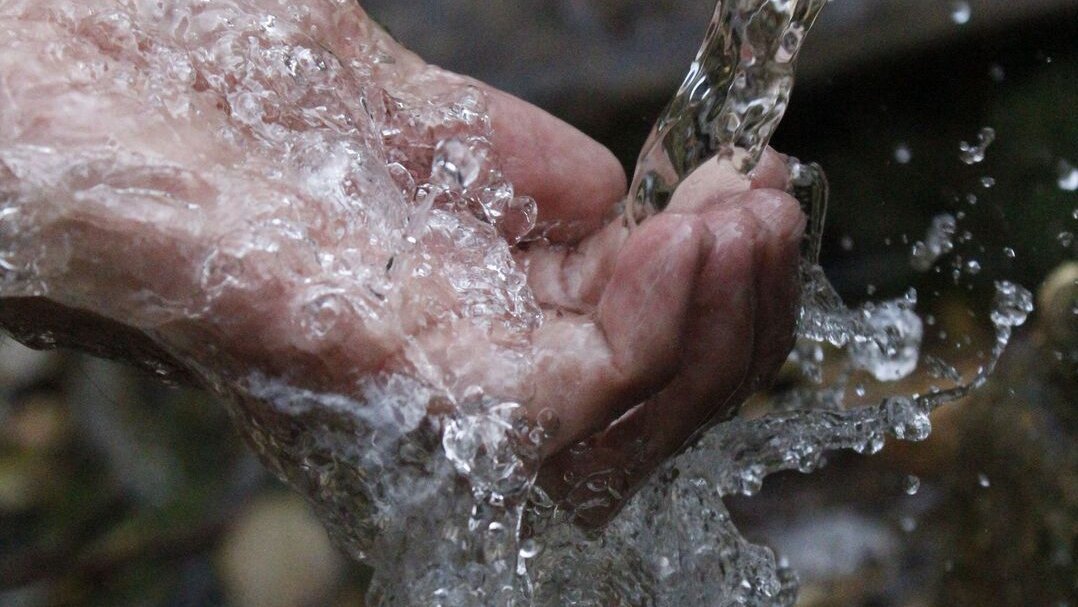 Klares Wasser fließt über eine geöffnete Hand