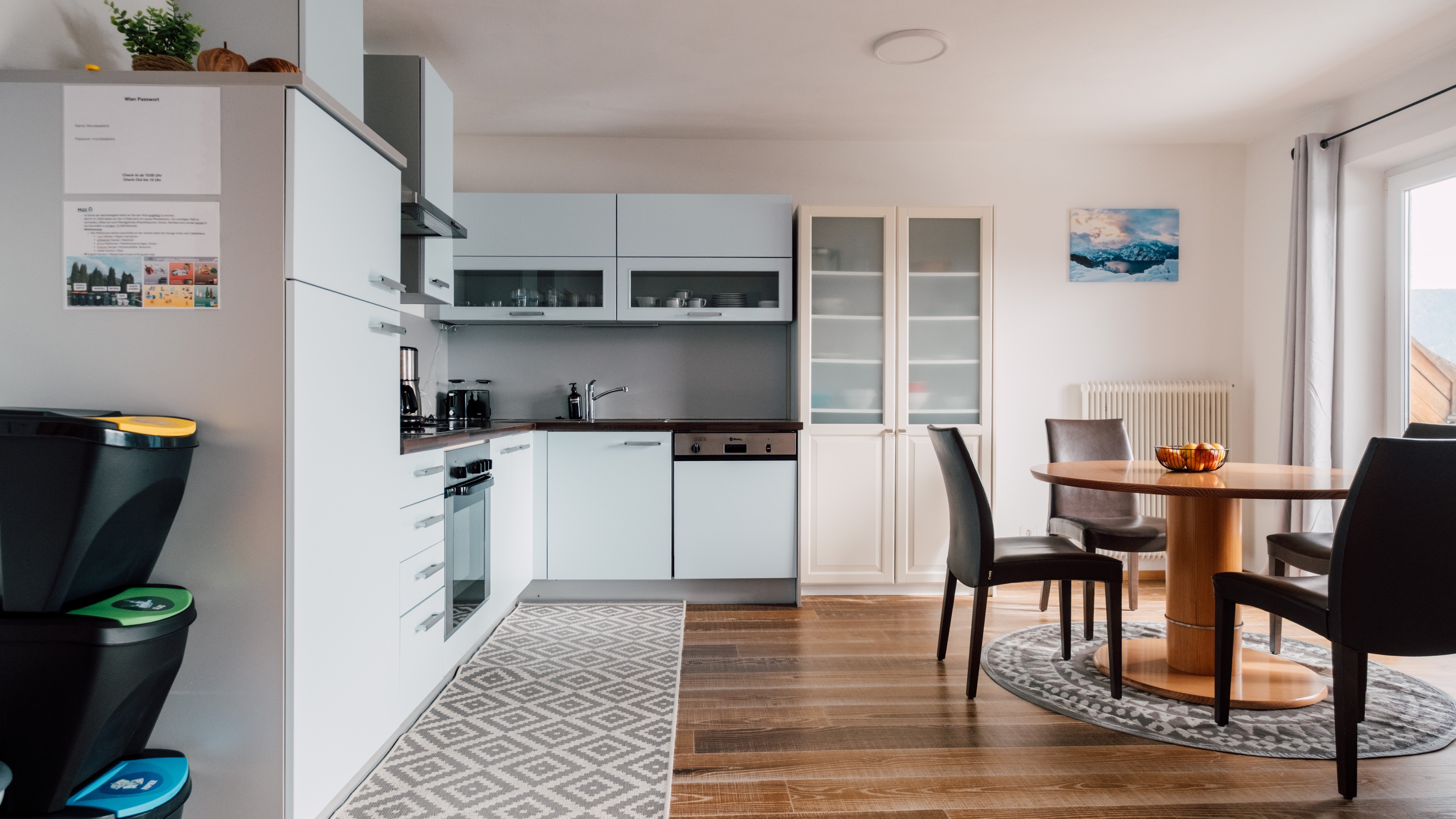 Moderne Küche im Detail Helle moderne Küche mit blauen Schränken und Essbereich, ausgestattet mit Geräten und Teppich.