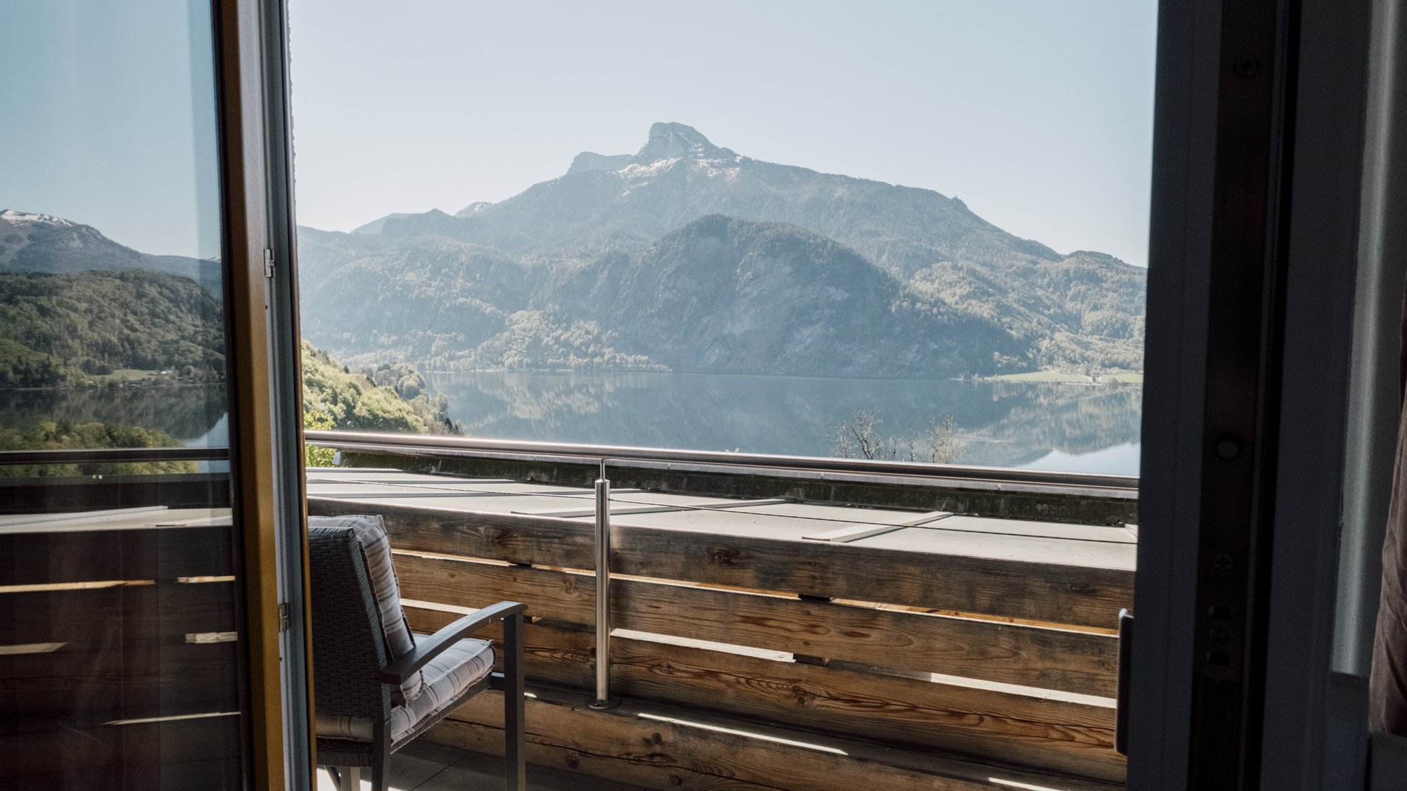 Offene Balkontür mit Blick auf eine Berglandschaft und die Natur im Hintergrund.