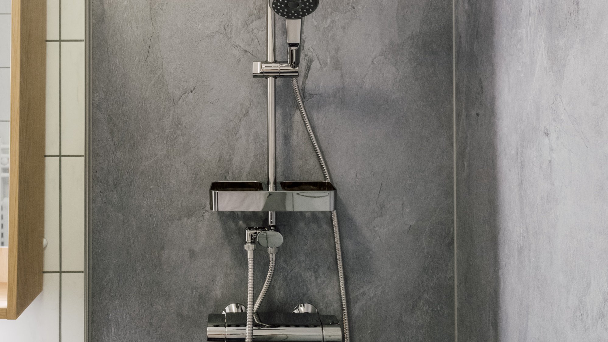 Ein modernes Duschsystem an einer strukturierten Wand in einem Badezimmer mit zeitgemäßem Design.