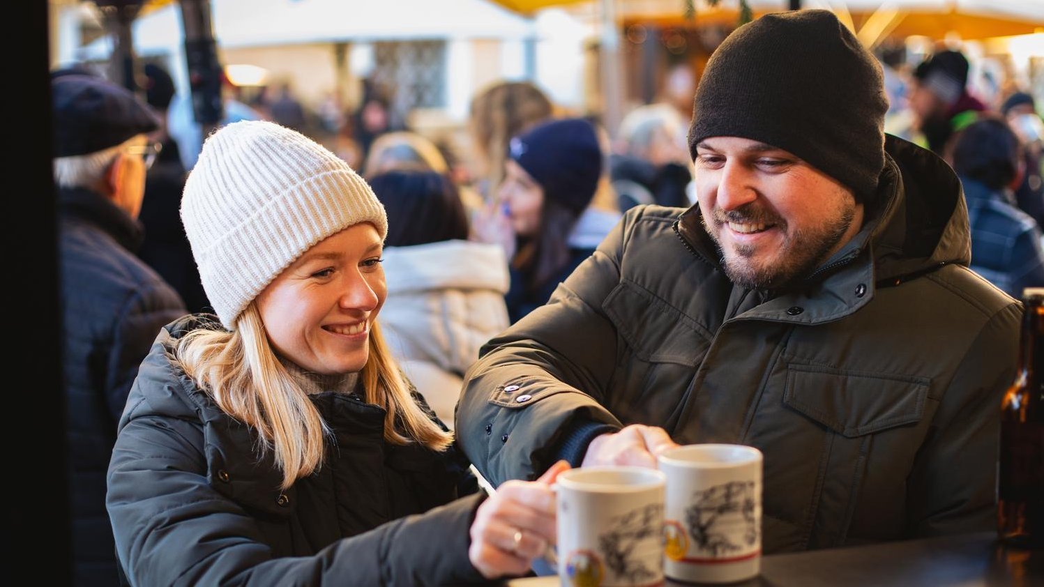 Zwei Personen genießen gemeinsam einen heißen Glühwein und die gemütliche Atmosphäre am Mondseer Adventmarkt. © TVB Mondsee Irrsee Markus Christ