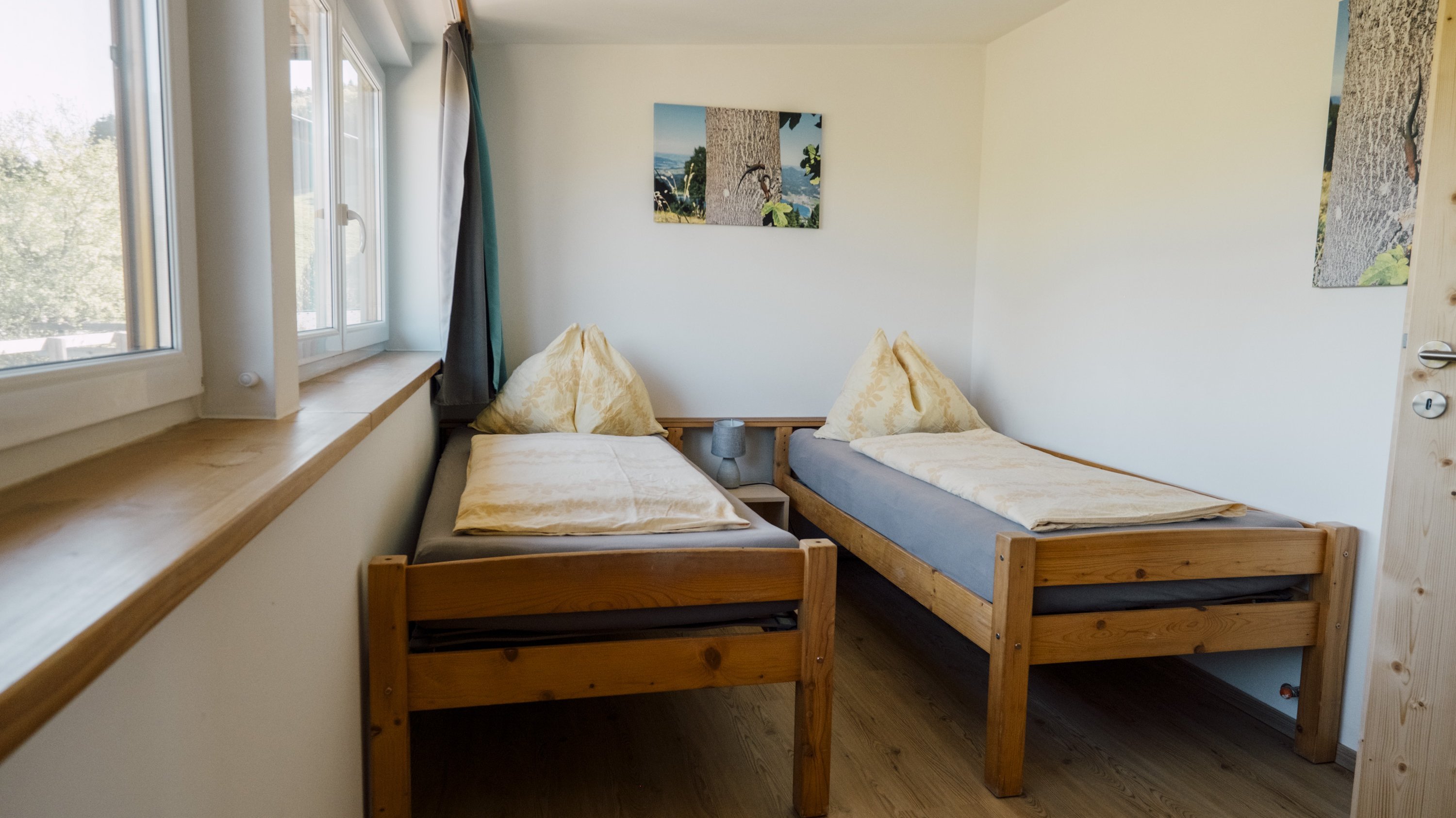 Schlafzimmer mit zwei Twin-Betten aus Holz und natürlichem Licht durch ein Fenster
