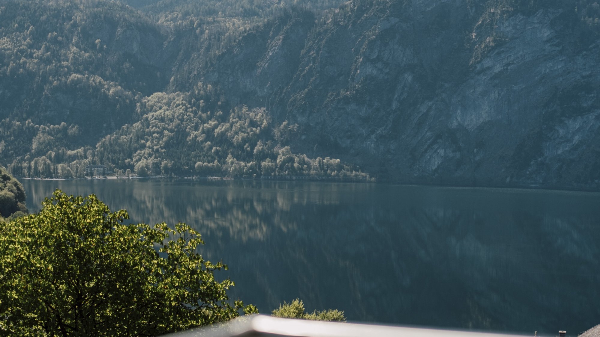 Serene mountain landscape featuring a clear lake under a blue sky with surrounding trees