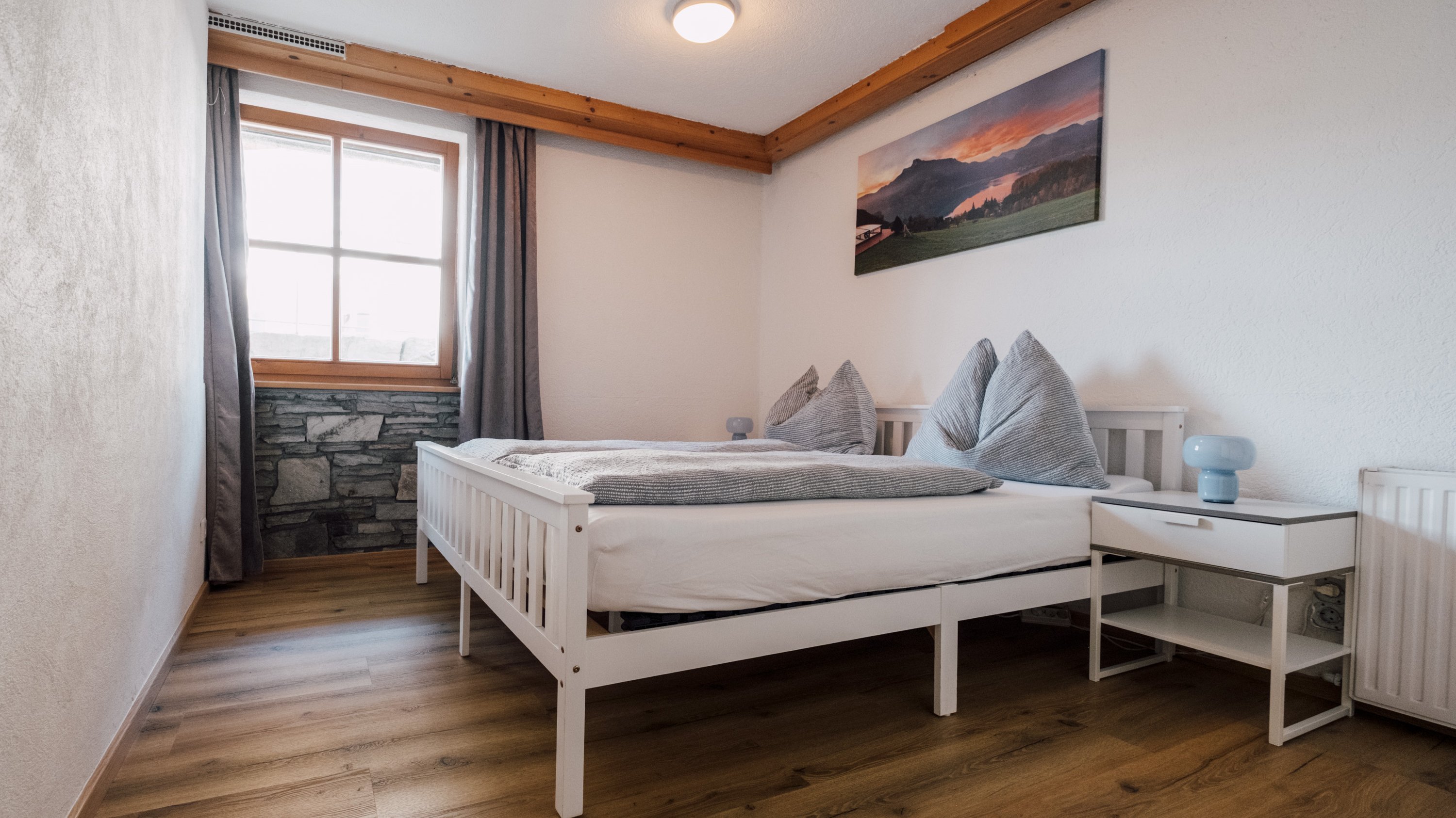 Schlafzimmer mit Bett, dekorativen Kissen und Fenster für Tageslicht, modernes Design.