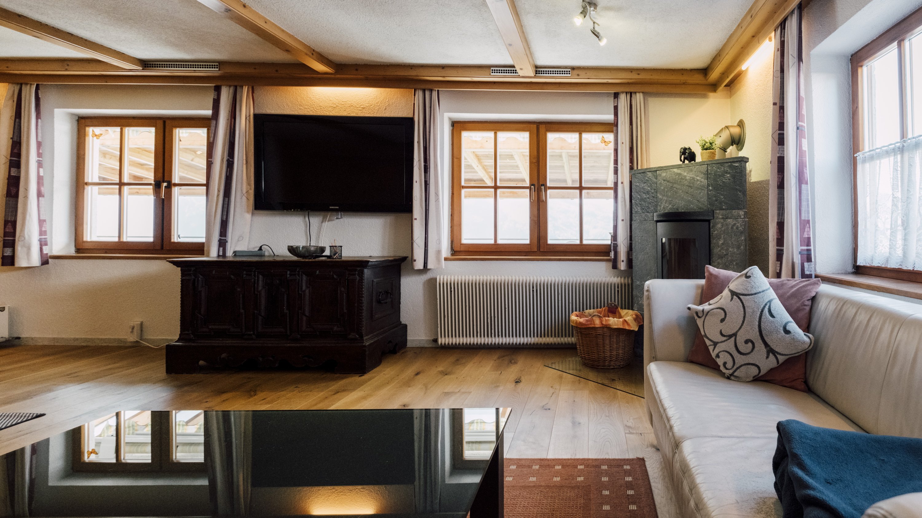 Gemütliches Wohnzimmer mit weißem Sofa und großen Fenstern, die viel Licht einlassen