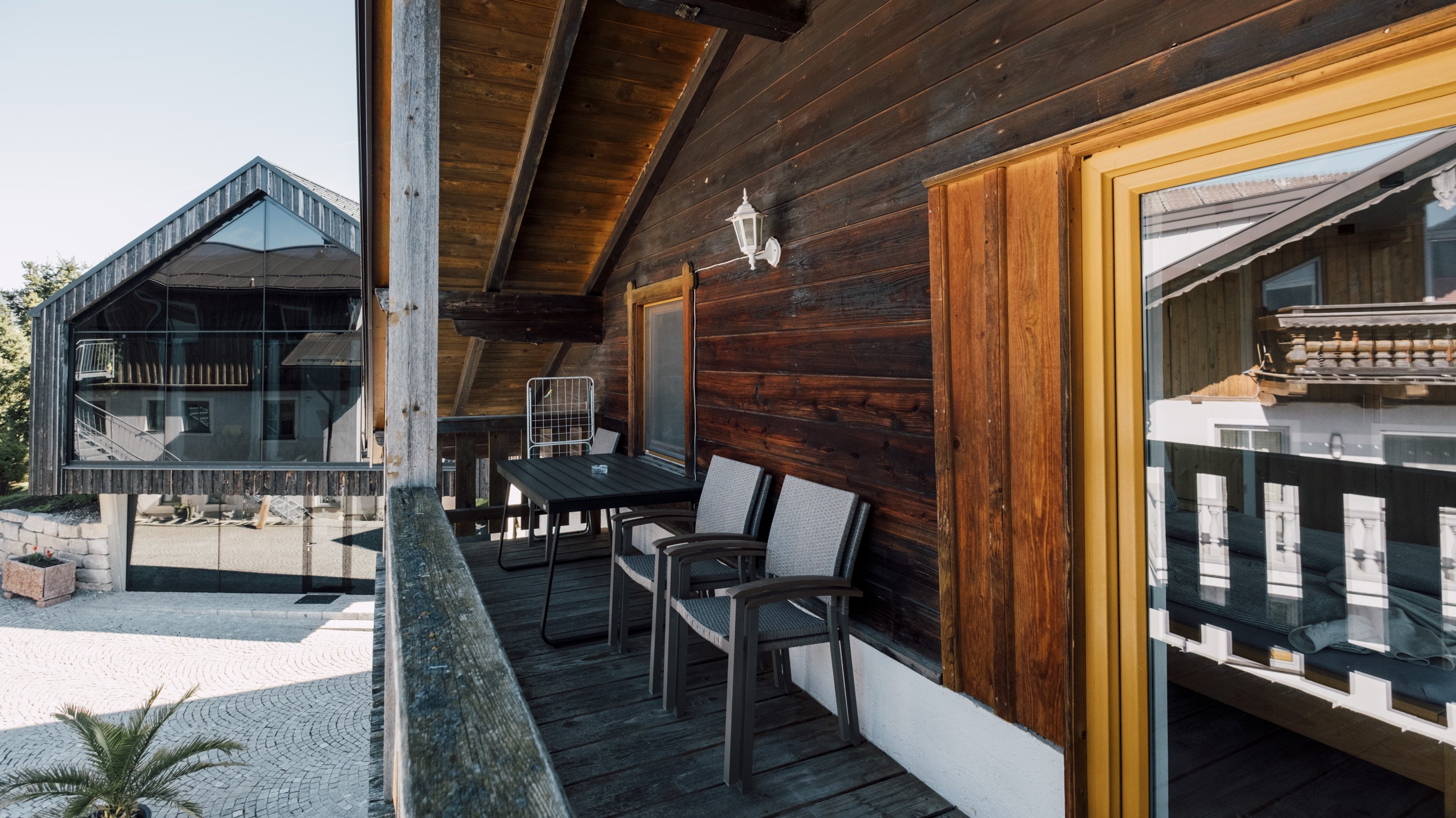 Balkon aus Holz mit Sitzgelegenheiten und Blick auf moderne Lodge und Berge im Hintergrund