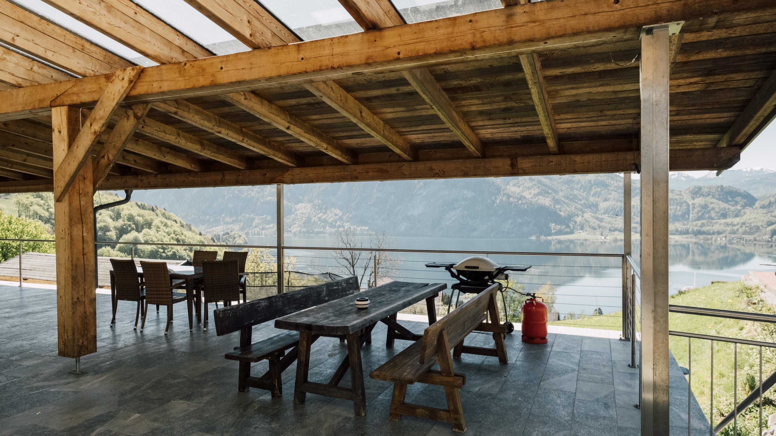 Holzverkleidete Terrasse mit großem Tisch und Stühlen, Blick auf eine Wasserlandschaft