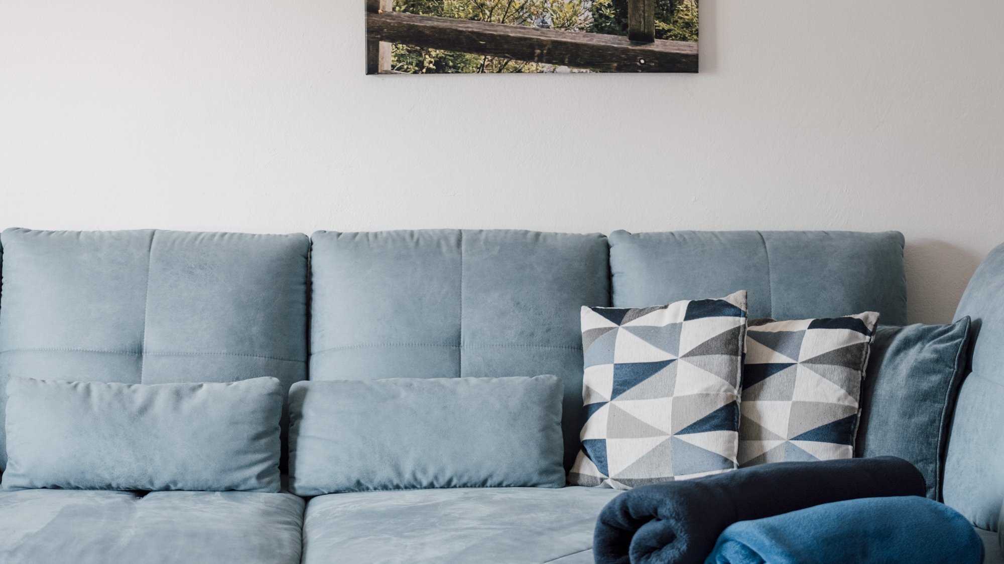 Moderner Wohnraum mit natürlichem Flair Heller Wohnraum mit modernem, blauem Sofa und Naturkunstwerk an der Wand, elegantes Interieur.