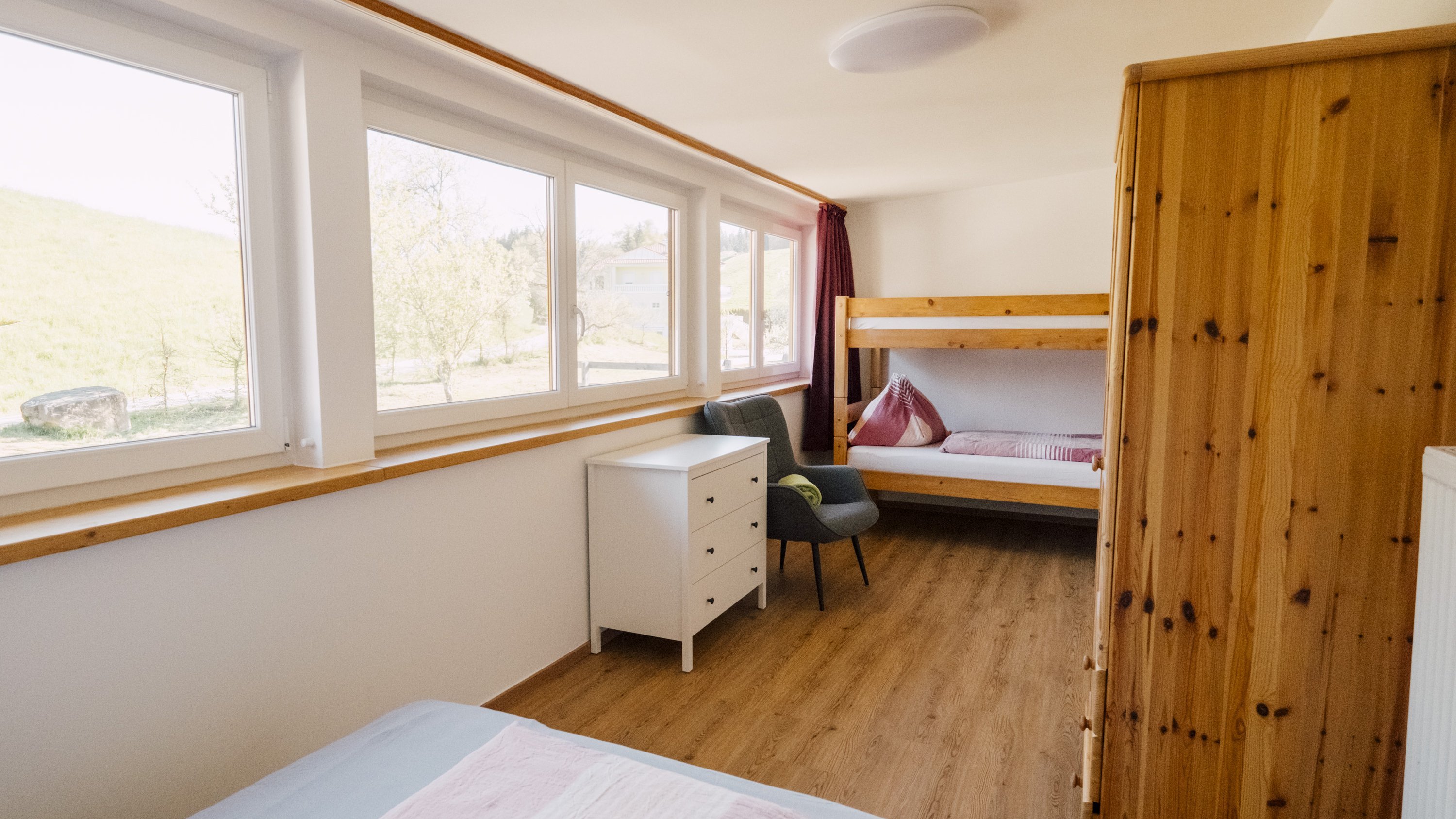 Minimalistisch eingerichtetes Kinderzimmer mit einem Etagenbett und großen Fenstern.