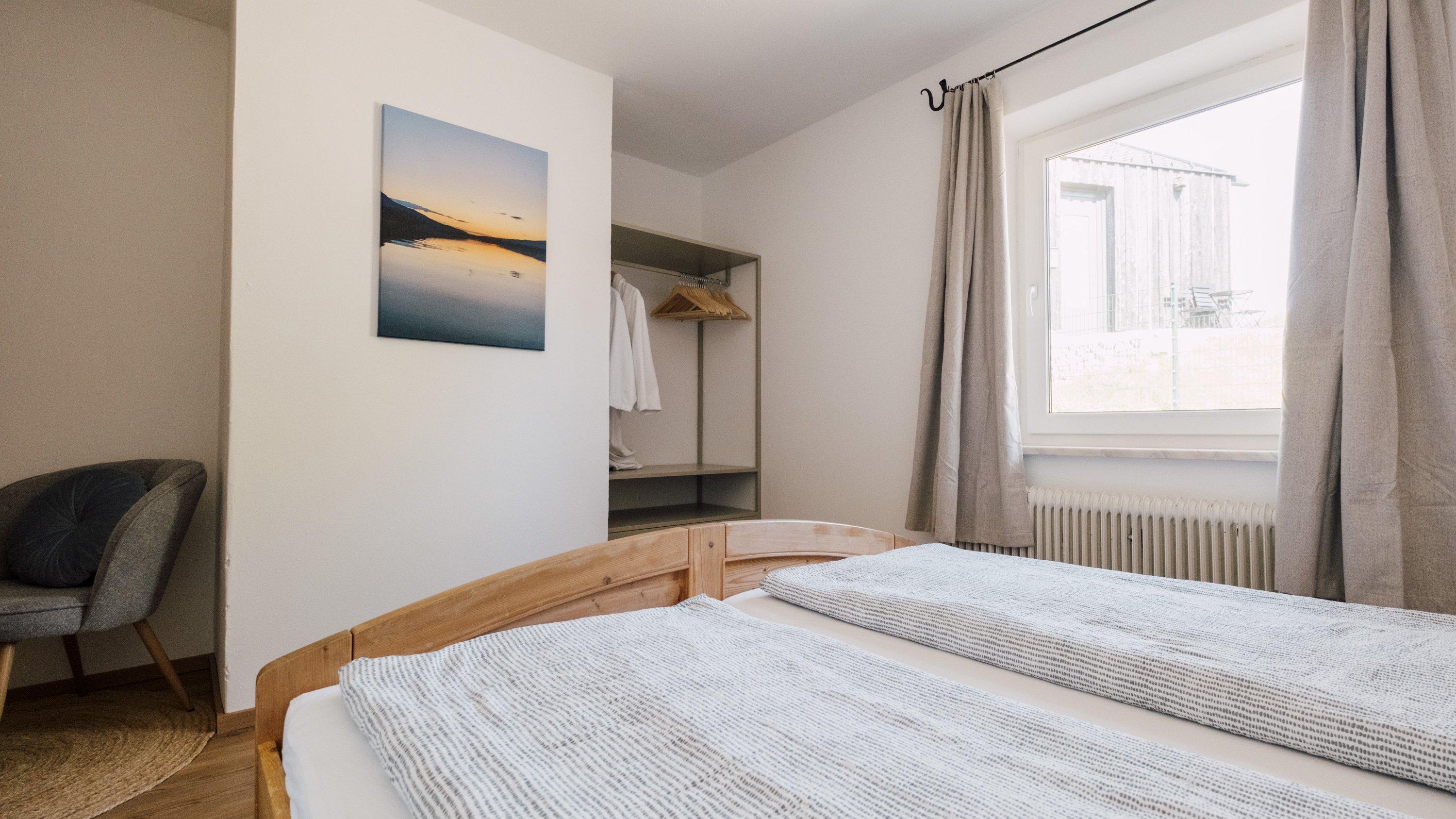 Minimalistisches Schlafzimmer mit natürlichem Licht Helles Schlafzimmer mit Holzbett, grauer Decke und gemütlichem Sessel im modernen Stil