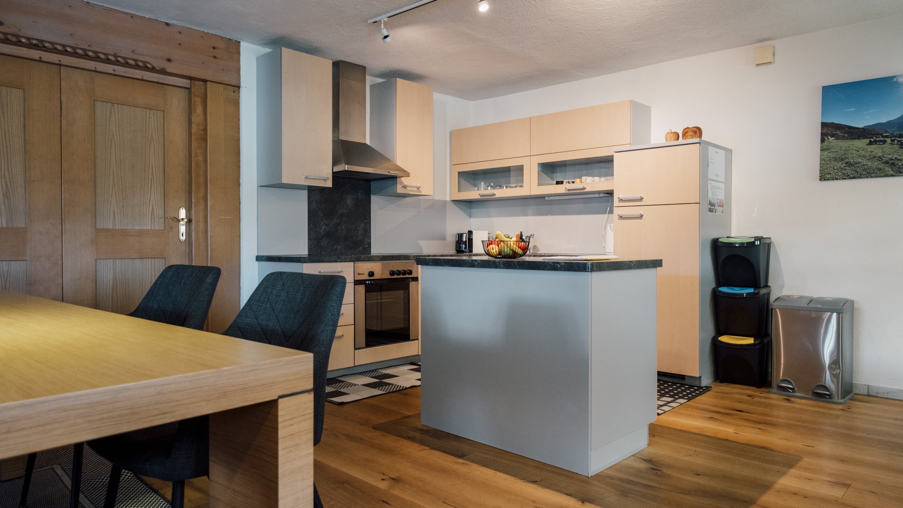 Moderne Küche mit Holzschränken, Insel und Essbereich aus Holz mit Stühlen zur Gestaltung des Wohnraums.