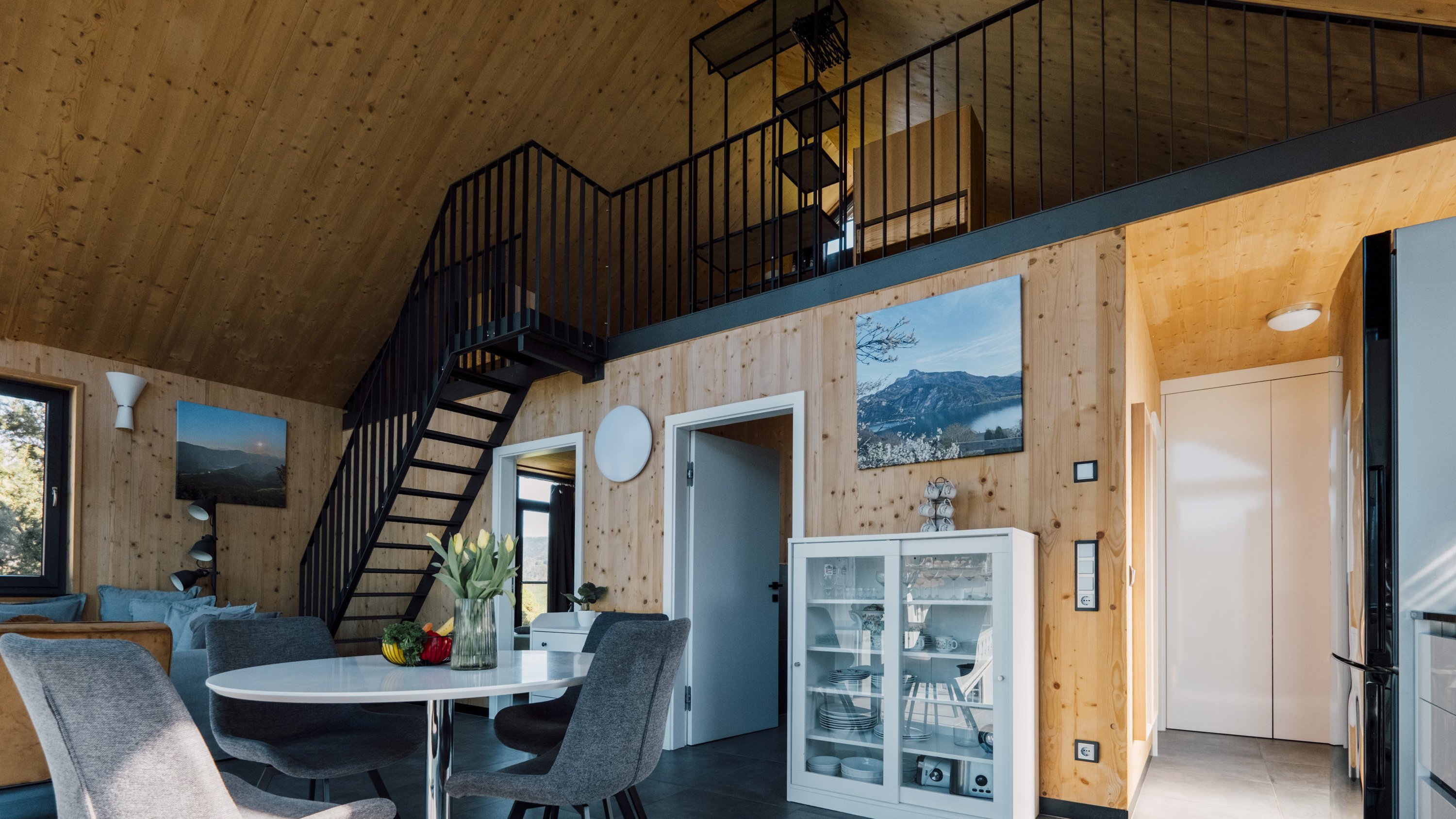 Helles Wohnzimmer mit Holzverkleidung, offener Wohnraum und Essbereich mit rundem Tisch